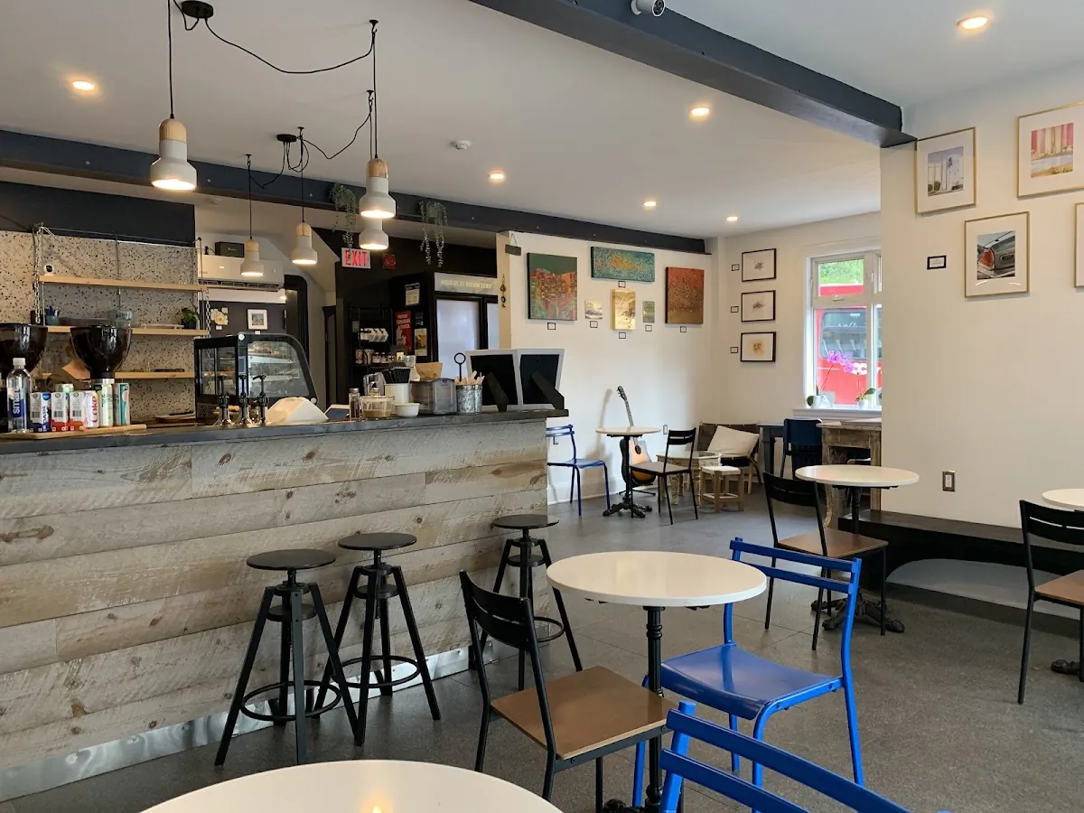 The main room at Café Miracle: a long counter with stools, pendant lamps, art on the walls and bright windows